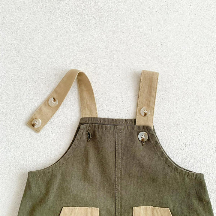 Olive green overalls with beige adjustable straps and button details on white textured background
