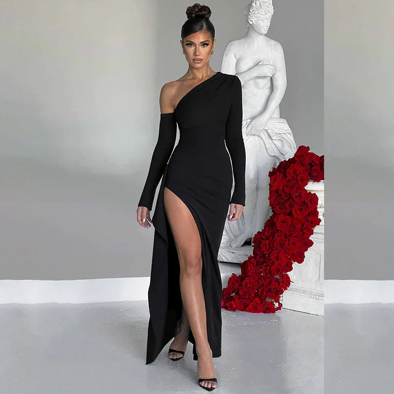 Woman in elegant black one-shoulder dress with thigh slit posing by white statue and red roses
