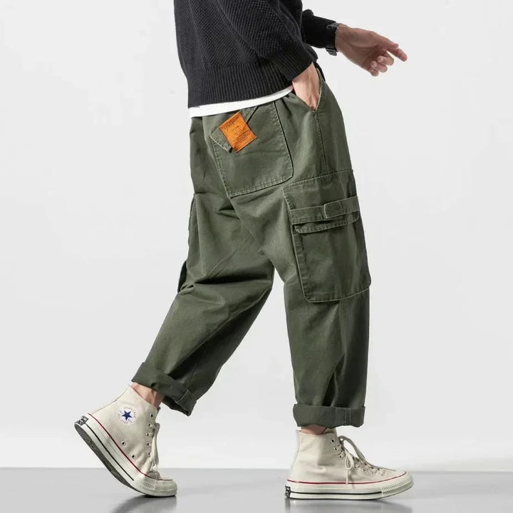 Person wearing olive green cargo pants with large pockets and white high-top sneakers