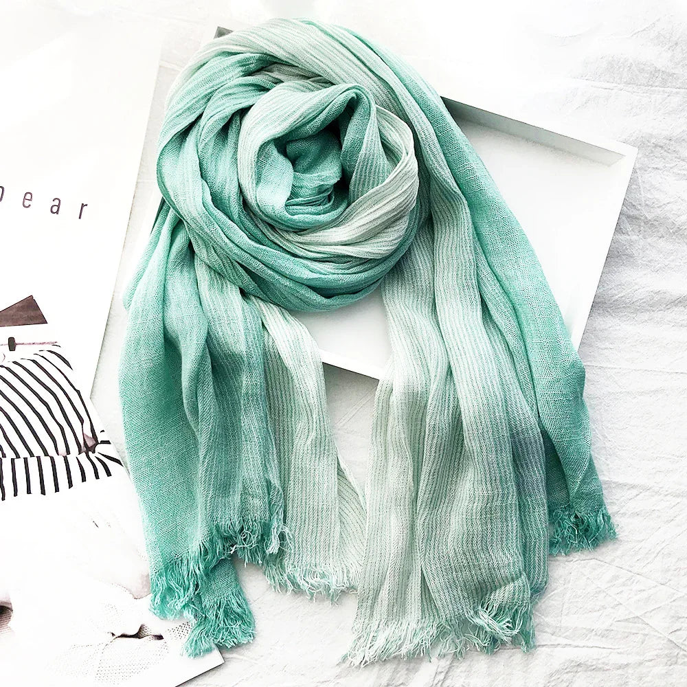 Soft textured green and white striped scarf with fringes, styled on white background with magazine