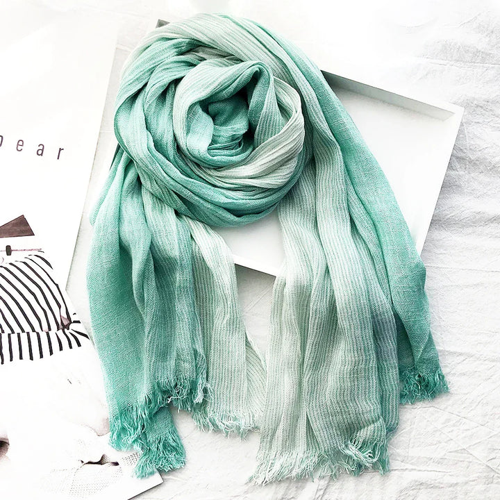 Soft textured green and white striped scarf with fringes, styled on white background with magazine