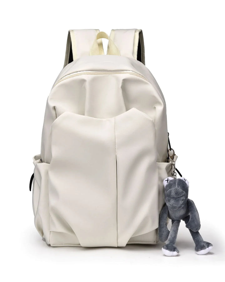 White backpack with padded straps and front pockets, featuring a gray plush frog keychain