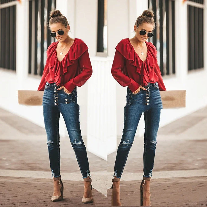 Woman in red ruffled blouse, high-waisted distressed jeans, and sunglasses in urban setting