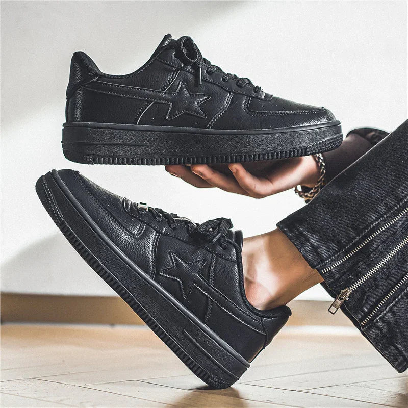Black leather casual sneakers with star design worn by person in black pants with zipper detail