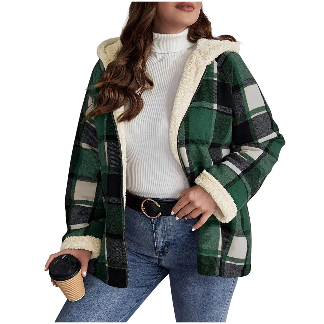 Woman wearing green plaid sherpa-lined hooded jacket with white turtleneck and jeans holding coffee cup