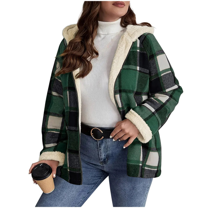 Woman wearing green plaid sherpa-lined hooded jacket with white turtleneck and jeans holding coffee cup