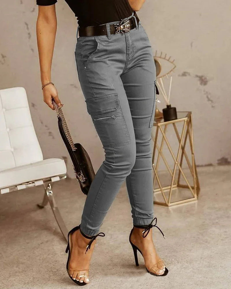 Woman wearing gray cargo pants with zipper pockets, black top, and high heel sandals indoors