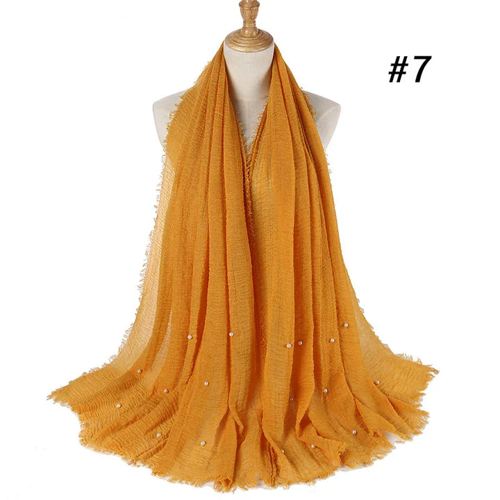 Mustard yellow textured scarf with small pearl accents displayed on a mannequin