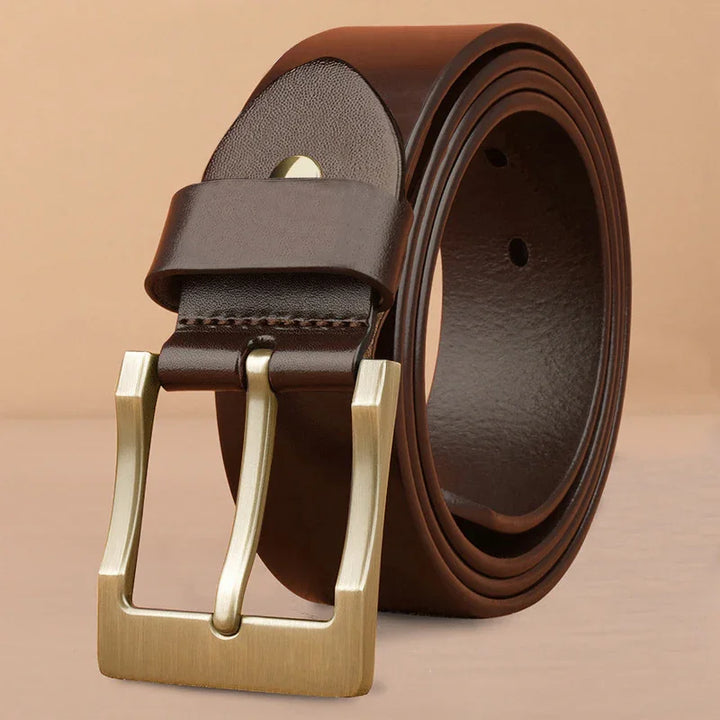 Rolled dark brown leather belt with brushed gold square buckle on beige background