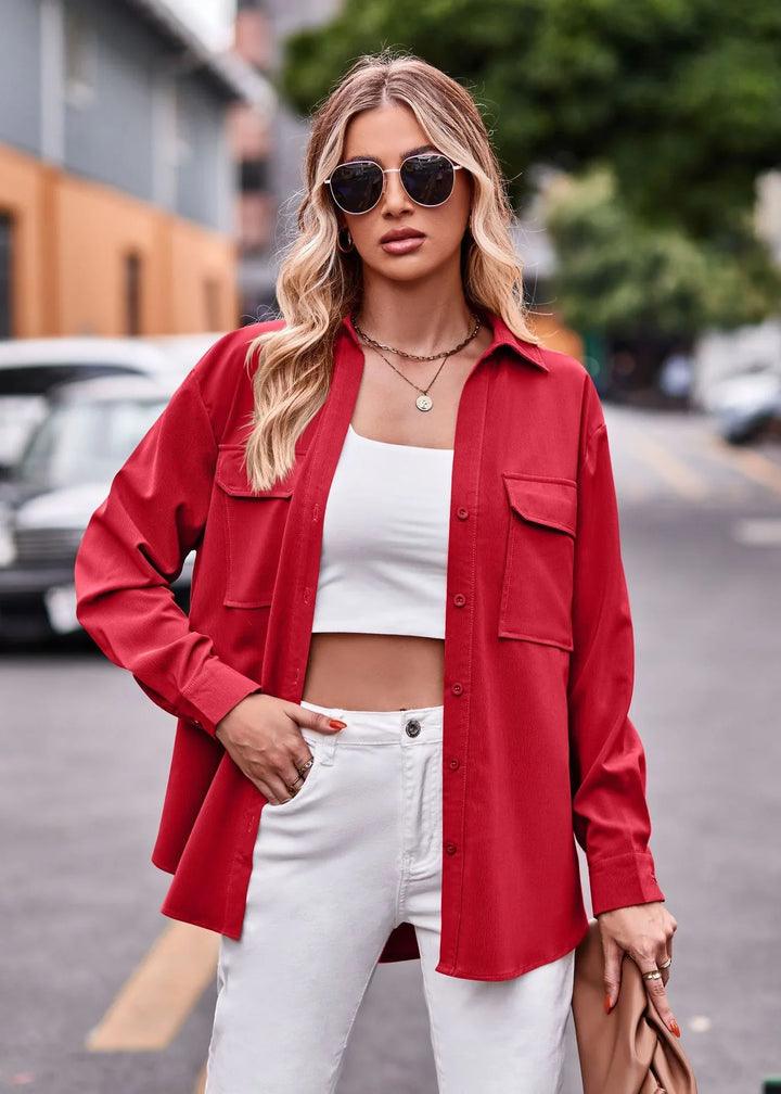 Blonde woman wearing oversized red shirt, white crop top, white pants, and sunglasses on city street