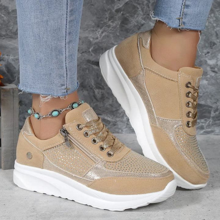 Beige women's casual sneakers with rhinestones and side zipper, worn with light blue jeans and turquoise anklet