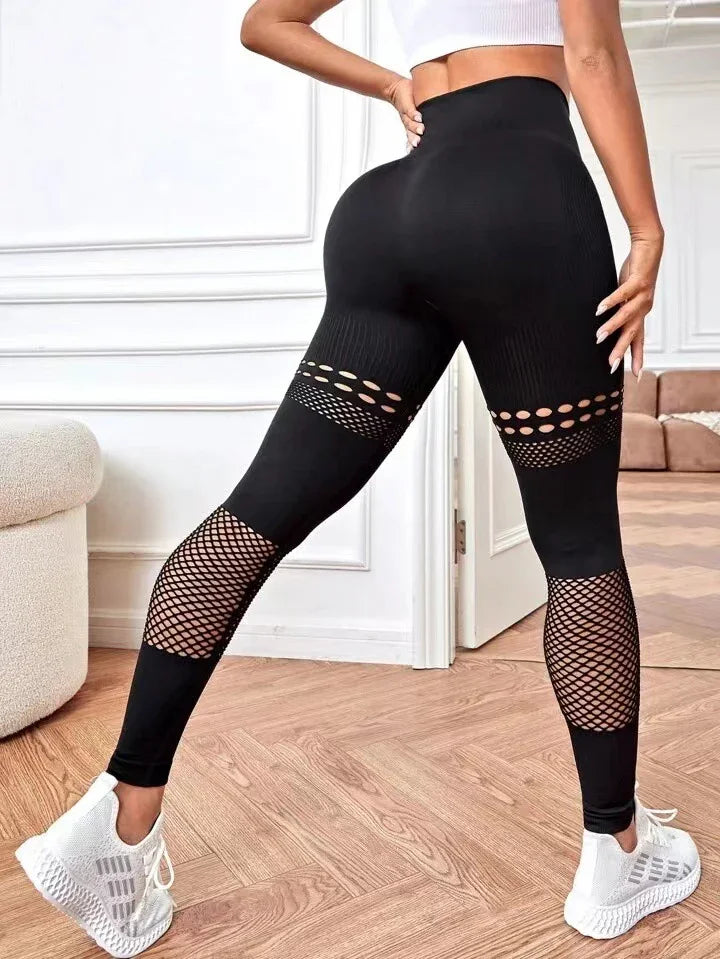 Woman wearing black high-waisted leggings with cutout and mesh details in a modern room