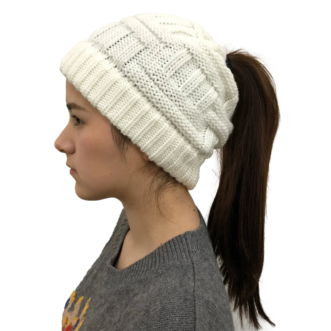 Side view of woman wearing a white knitted ponytail beanie and gray sweater