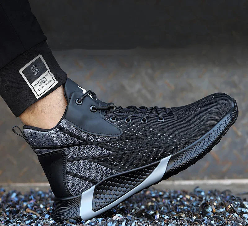 Black and gray athletic sneaker with textured sole worn with black pants against a gray background