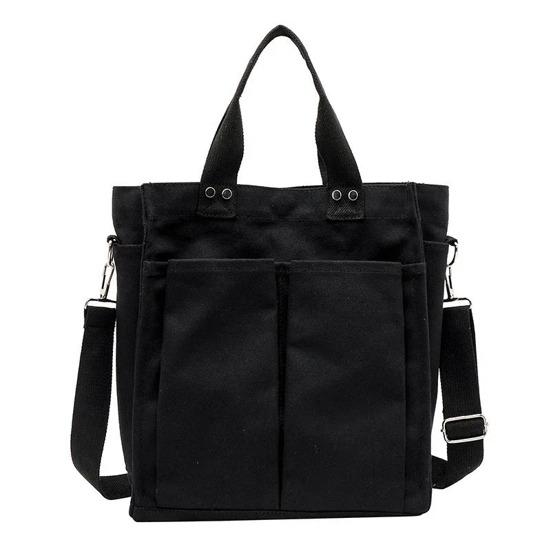 Black canvas tote bag with dual front pockets, detachable shoulder strap, and sturdy handles