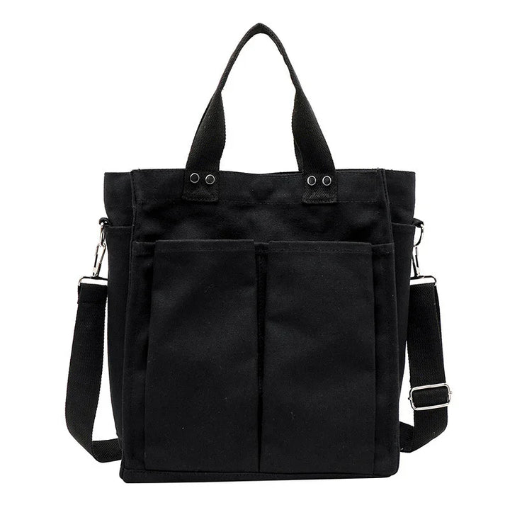 Black canvas tote bag with dual front pockets, detachable shoulder strap, and sturdy handles