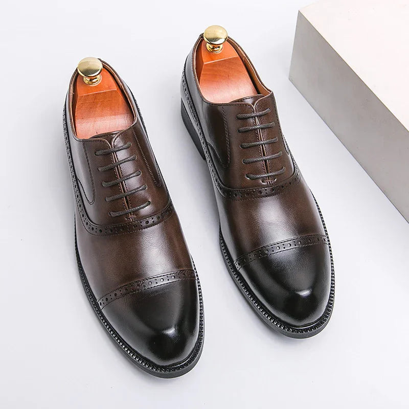 Pair of brown leather dress shoes with black cap toes and brogue detailing on white background