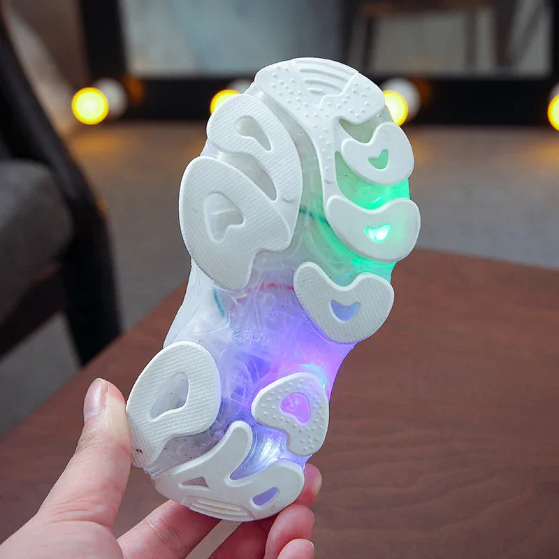 Hand holding white sole of light-up kids sneaker with colorful glowing LED lights