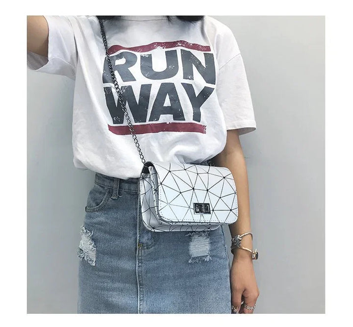 Woman wearing white RUNWAY t-shirt, distressed denim skirt, and geometric white crossbody bag with chain strap