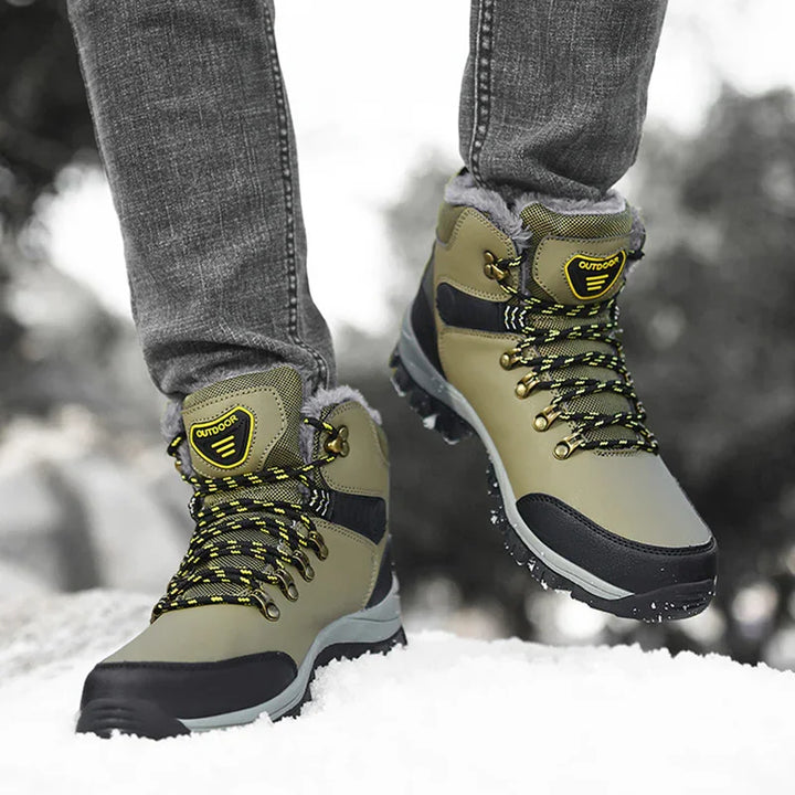 close-up of green and black outdoor winter boots with yellow laces worn on snow