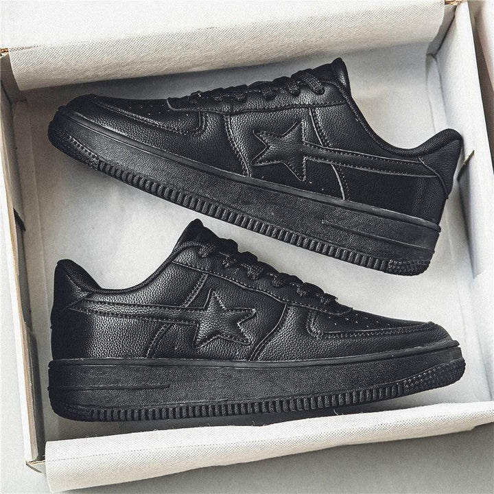 Pair of black leather sneakers with star design in white shoe box on white background