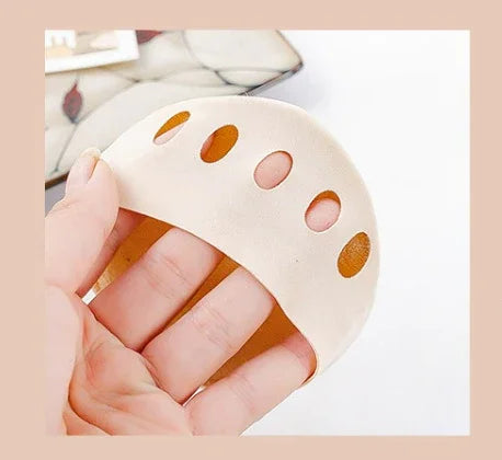 Hand holding nude shoe insert pad with breathable holes on beige background