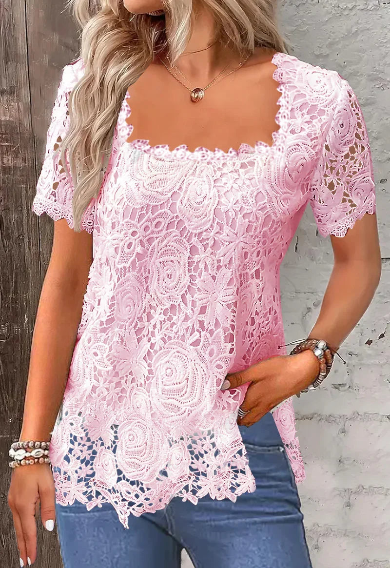 Woman wearing a light pink floral lace short sleeve blouse with scalloped edges and blue jeans