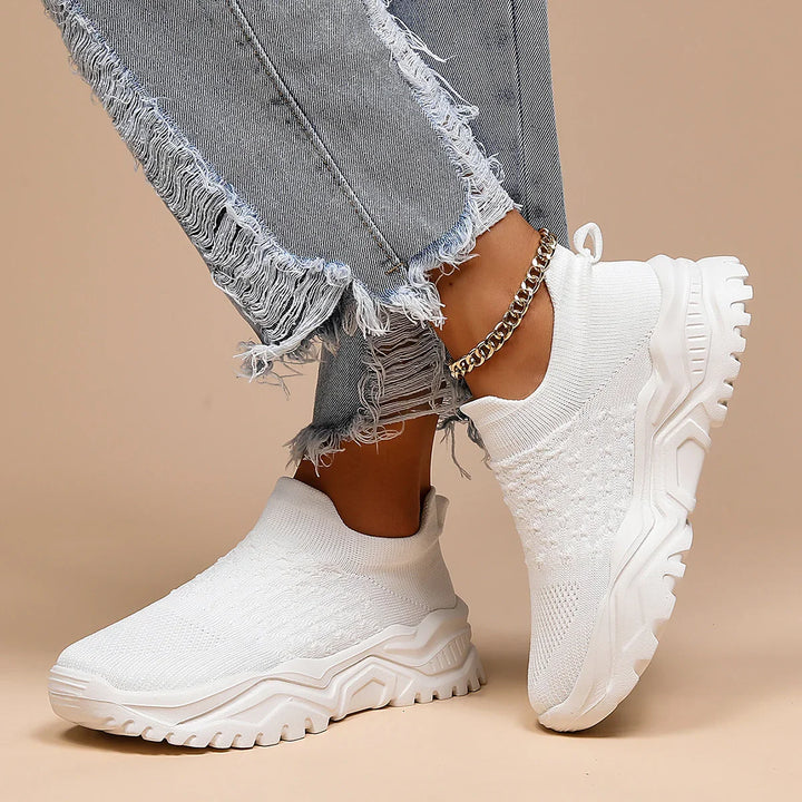 White knit sock sneakers with thick sole worn with shredded gray denim jeans and gold anklet