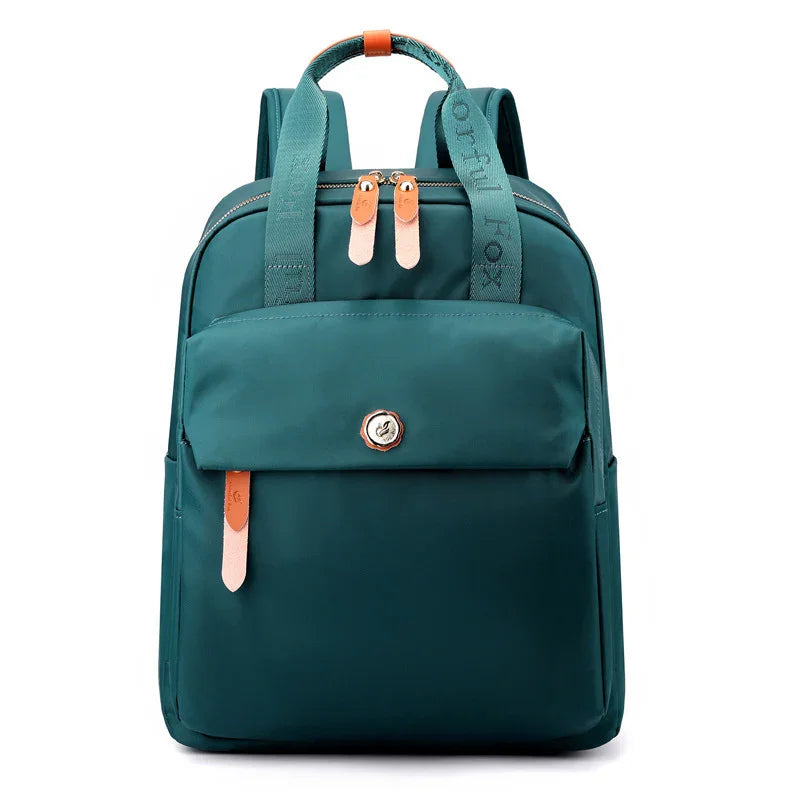 Teal backpack with front pocket, dual leather zipper pulls, padded straps, and top handle