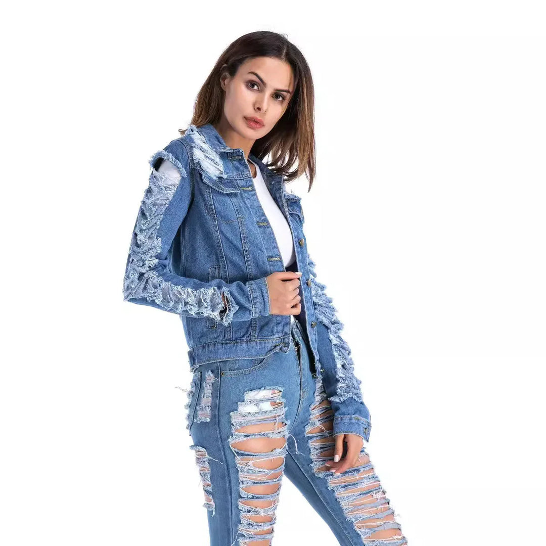 Woman wearing distressed blue denim jacket and heavily ripped jeans against white background