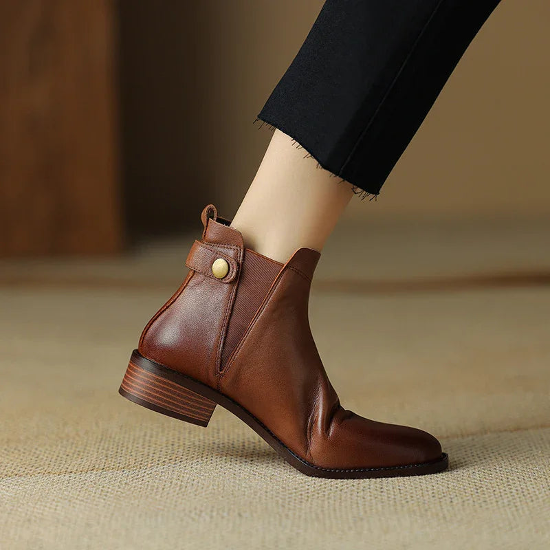 brown leather ankle boot with low stacked heel and button strap detail worn with black cropped pants