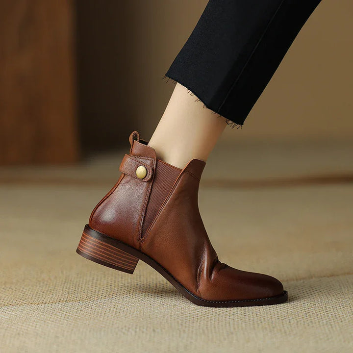 brown leather ankle boot with low stacked heel and button strap detail worn with black cropped pants
