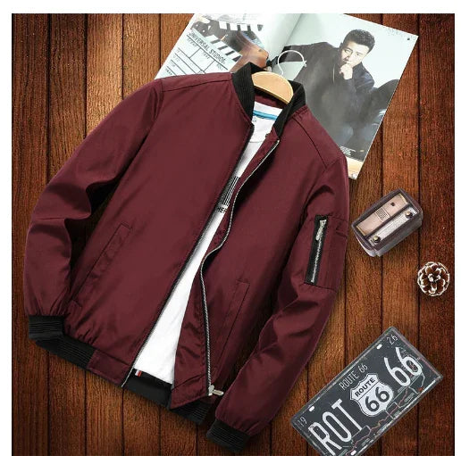Maroon bomber jacket with black collar and zipper on wooden floor with Route 66 sign and magazine