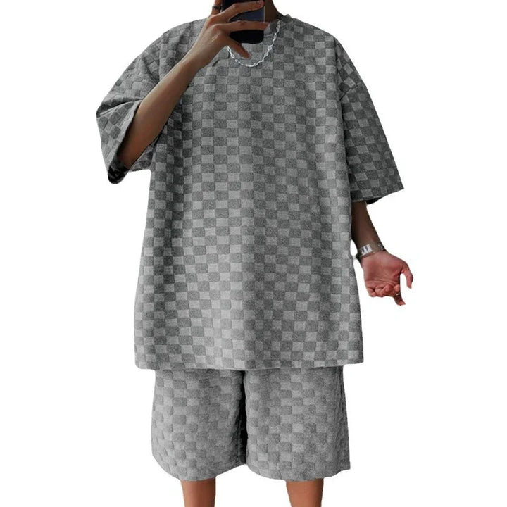 Man wearing loose grey checkered short sleeve shirt and matching shorts outfit