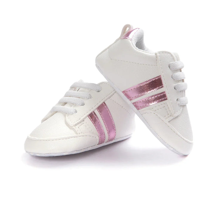 White baby sneakers with metallic pink stripes and laces on a white background