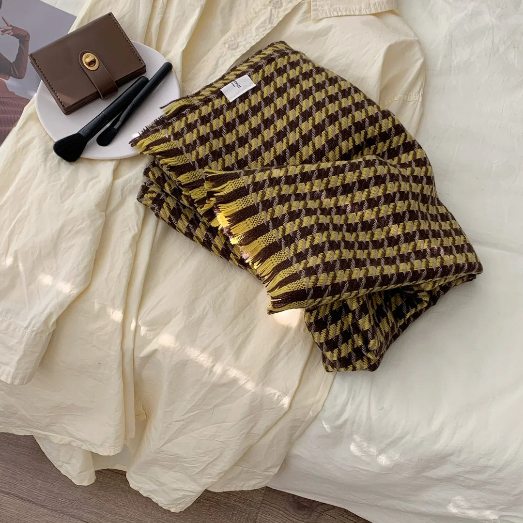 Folded brown and yellow checkered scarf on cream fabric shirt with brown wallet and black makeup brushes