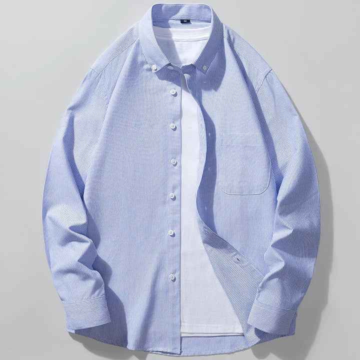 Blue and white thin striped button-up shirt layered over a plain white t-shirt on gray background