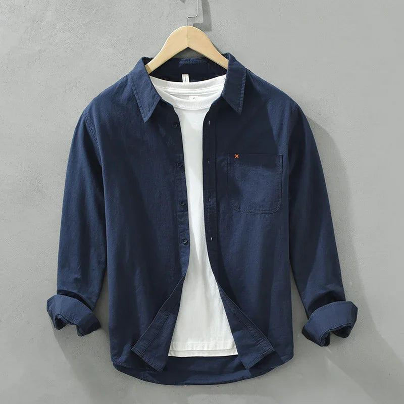 Navy blue casual button-up shirt with chest pocket layered over a white crew neck t-shirt on hanger