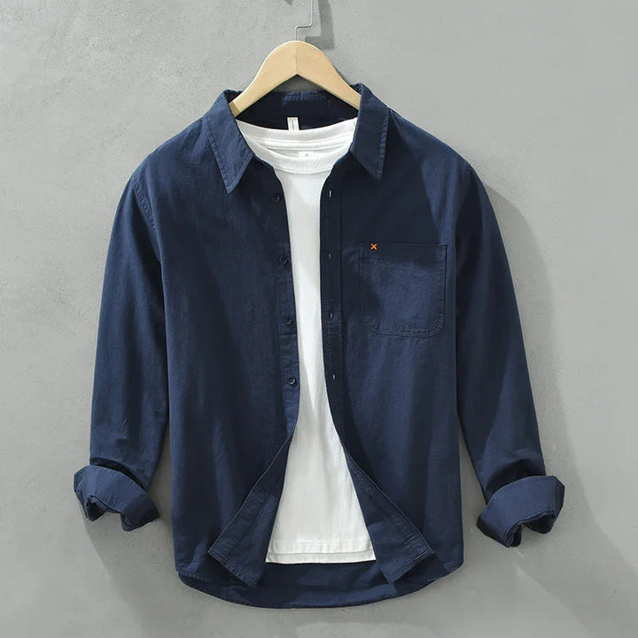 Navy blue casual button-up shirt with chest pocket layered over a white crew neck t-shirt on hanger