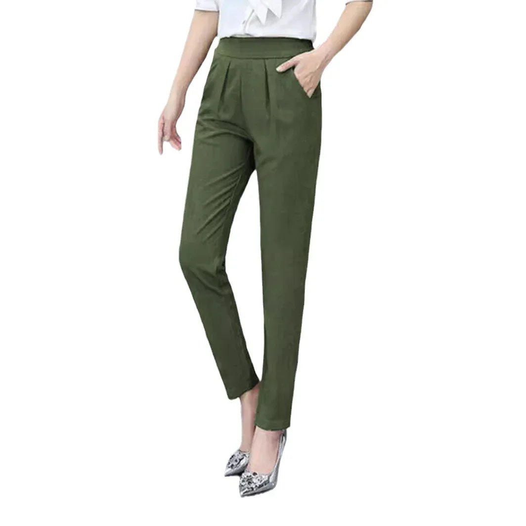 Woman wearing high-waisted olive green tapered pants with side pockets and silver pointed heels
