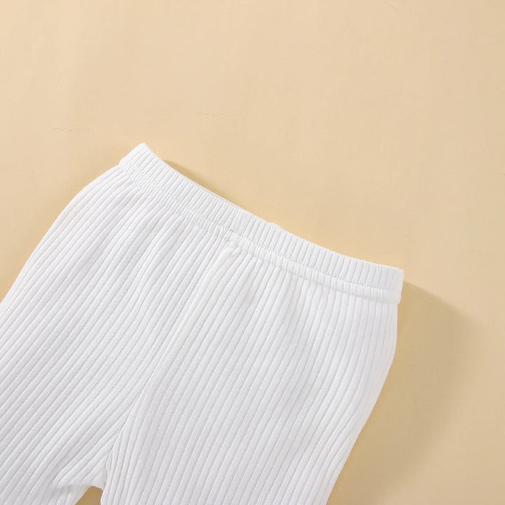 Close-up of white ribbed knit pants with elastic waistband on beige background