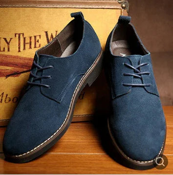Pair of stylish navy blue suede men's casual lace-up shoes on wooden surface