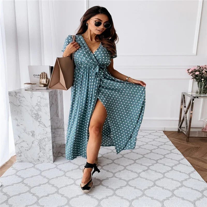 Woman in teal polka dot wrap dress with slit, black espadrille wedges, brown tote bag, sunglasses indoors