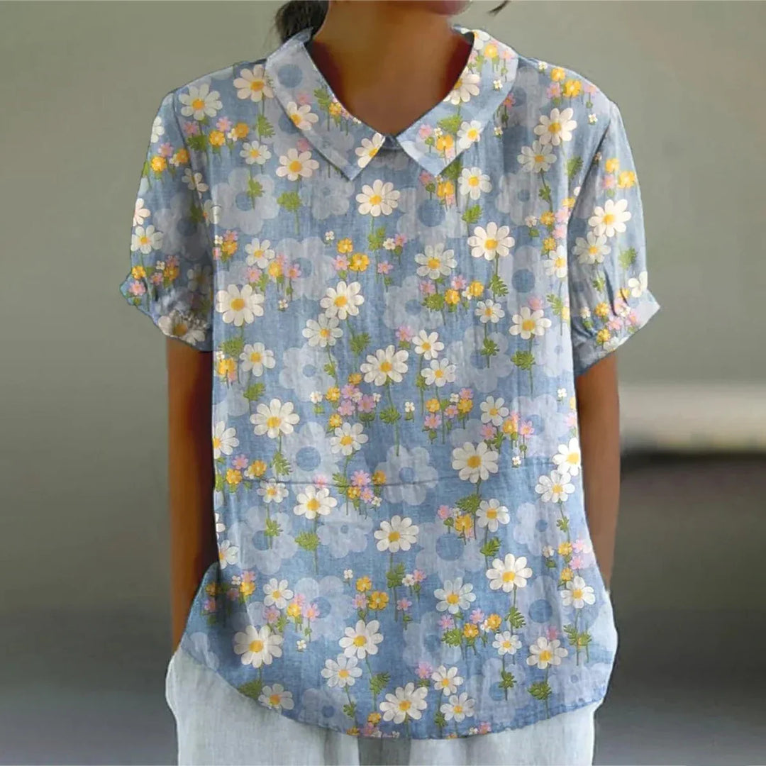 Woman wearing blue short-sleeve shirt with white and yellow floral print and collar