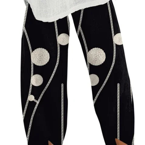 Black pants with white circular patterns and vertical chain-like lines, paired with a white top