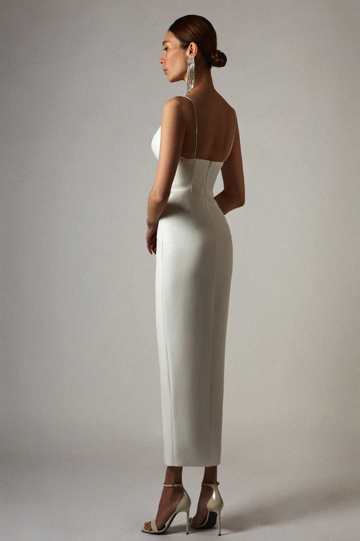 Woman in white form-fitting midi dress with spaghetti straps and high heel sandals in studio