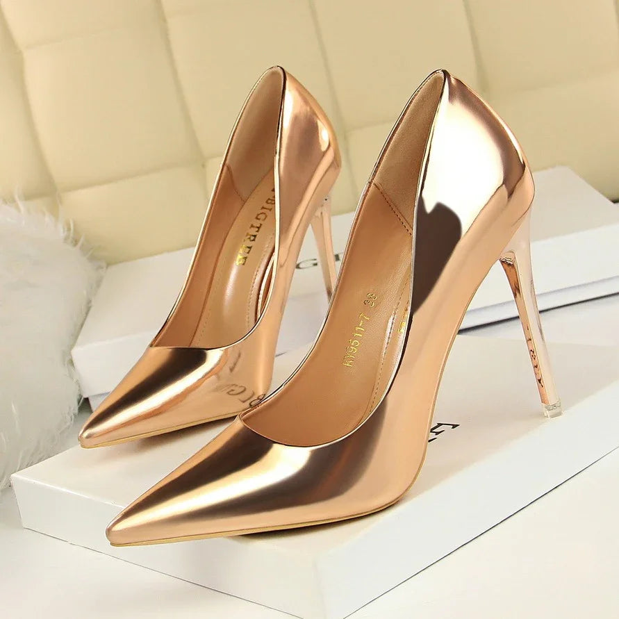 Pair of shiny rose gold stiletto high heels on white boxes in a soft beige setting