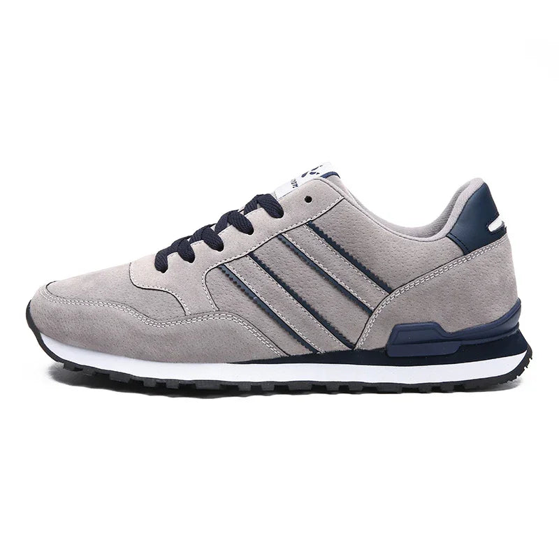 Gray sneaker with navy details, black laces, and white sole on white background