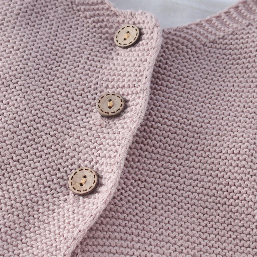 Close-up of soft pink knitted fabric with three decorative wooden buttons