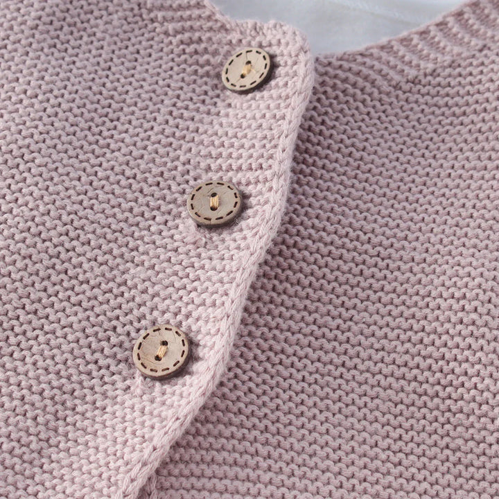 Close-up of soft pink knitted fabric with three decorative wooden buttons